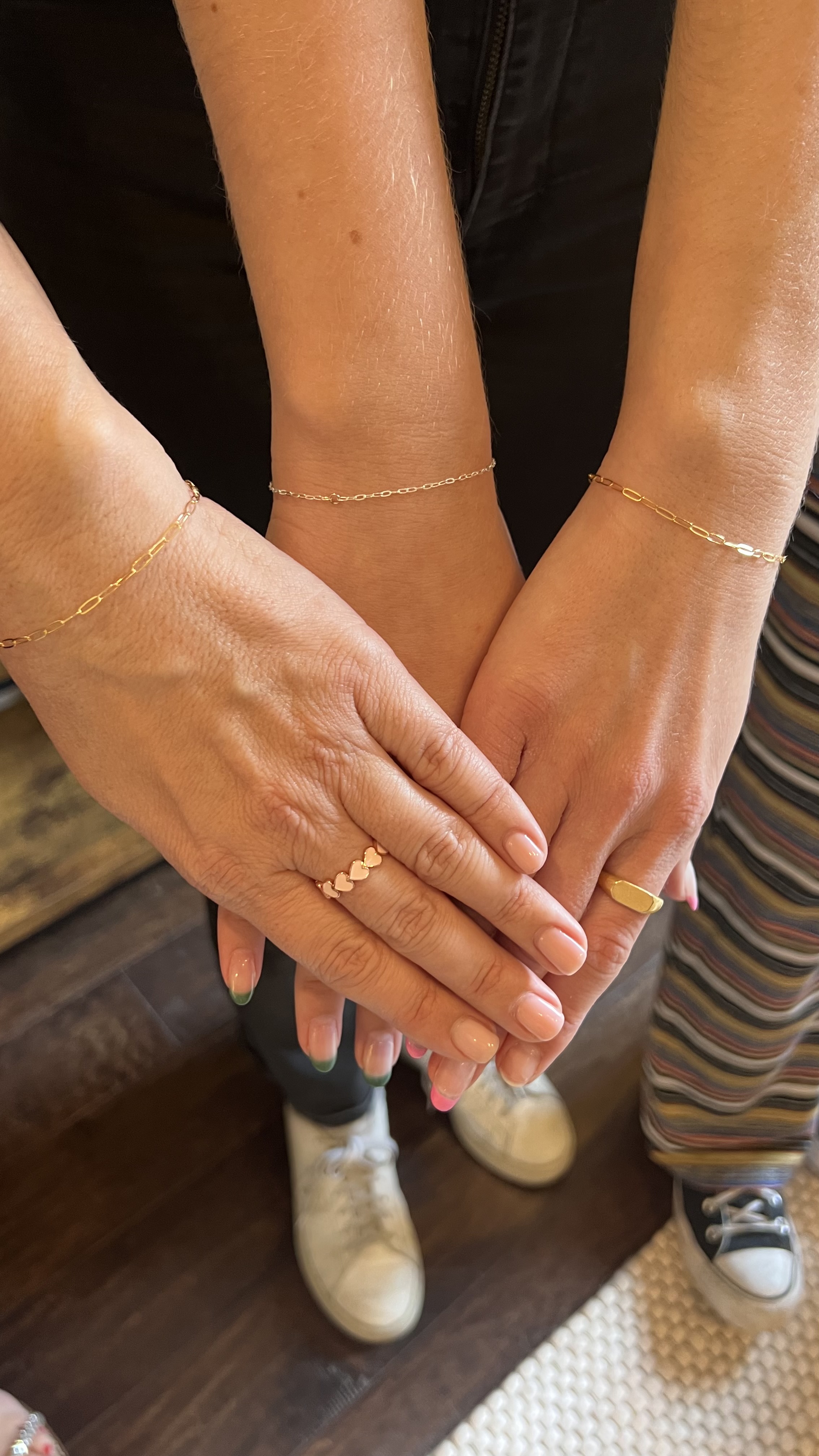Three women wearing 14k gold permanent bracelets