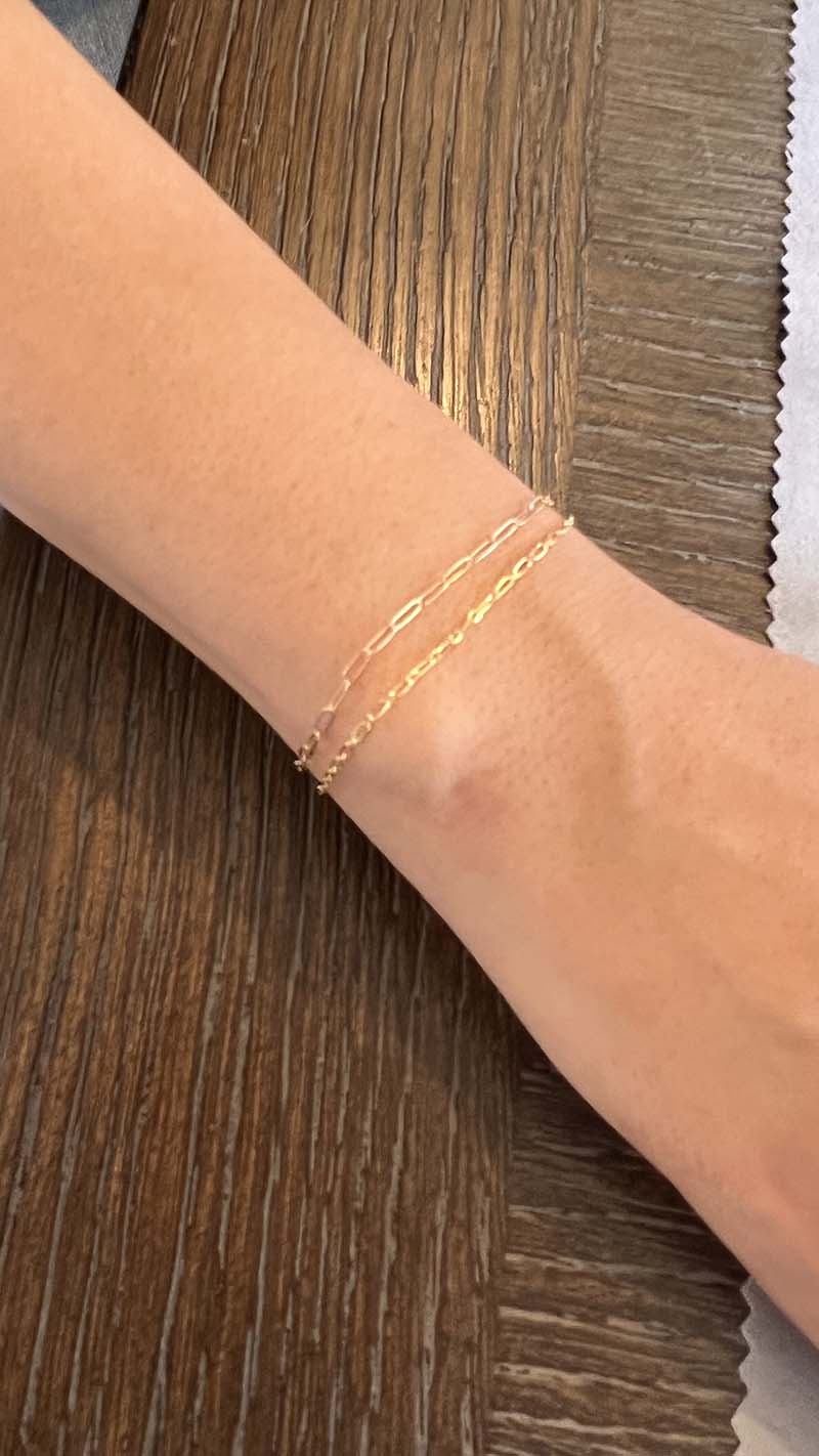 A woman wearing two 14k gold permanent bracelets